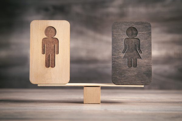 Male and female wooden symbols on balance scales.